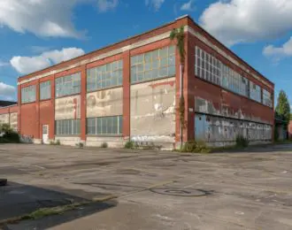 Old abandoned red brick warehouse building with broken windows