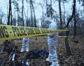 Crime scene marked with police warning tape as coroners investigate a murder